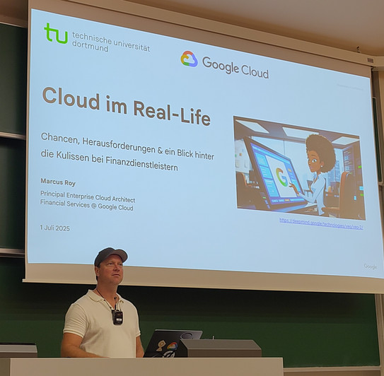 Dr. Marcus Roy hinter einem Pult, im Hintergrund die erste Slide mit dem Titel seiner Präsentation