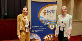 Lisa Schned and Dr. Lisa Gussek next to a poster of the conference